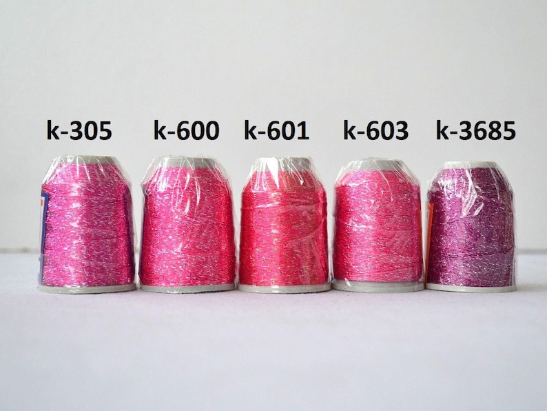 May include: Five spools of metallic embroidery thread in various shades of pink and purple. The spools are labeled with the following numbers: k-305, k-600, k-601, k-603, and k-3685.