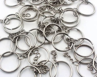 May include: A large pile of silver key rings with attached chains. The key rings are all the same size and are arranged in a random pattern.
