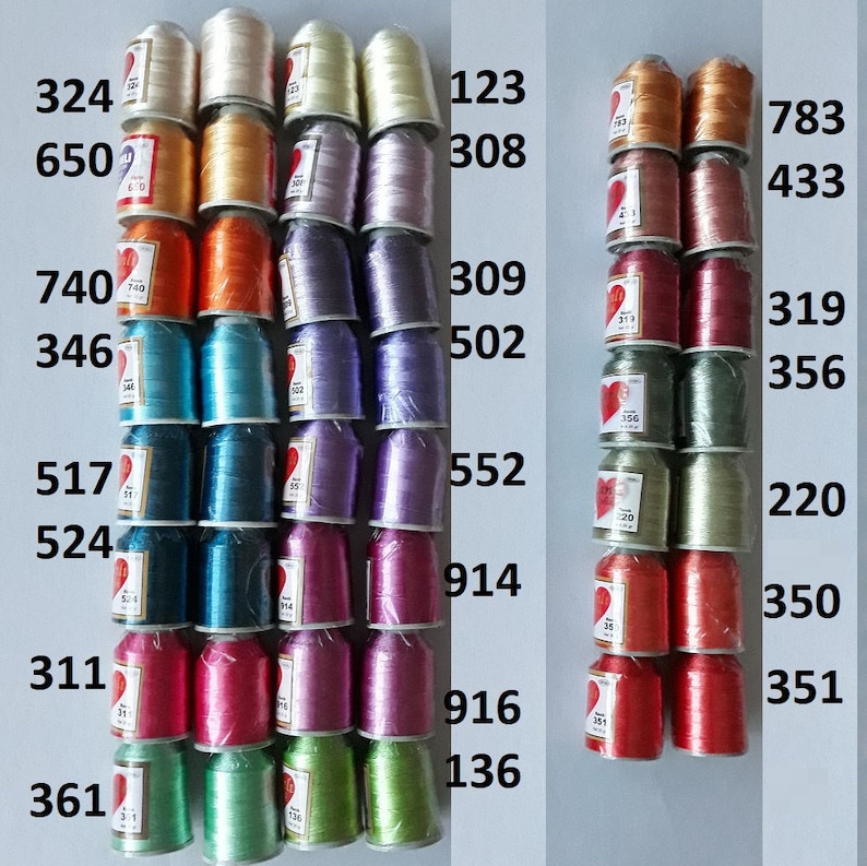 May include: A collection of spools of thread in various colors, including gold, silver, red, green, blue, and purple. The spools are arranged in rows and columns, and each spool has a number printed on it. The numbers are 324, 650, 740, 346, 517, 524, 311, 361, 123, 308, 309, 502, 552, 914, 916, 136, 783, 433, 319, 356, 220, 350, 351.