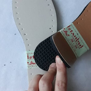 May include: A white leather shoe sole with a black rubber heel and a label that says "Istanbul Ayakkabı Kutusu 38-39".