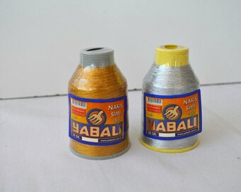 May include: Two spools of gold and silver embroidery thread with the brand name "YABALI" and the text "NAKIŞ SİMİ" on the labels.
