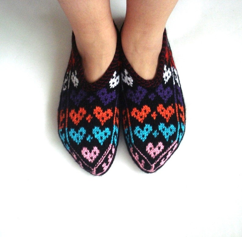 May include: A pair of black knitted slippers with a colorful heart pattern in shades of pink, blue, orange, and white.
