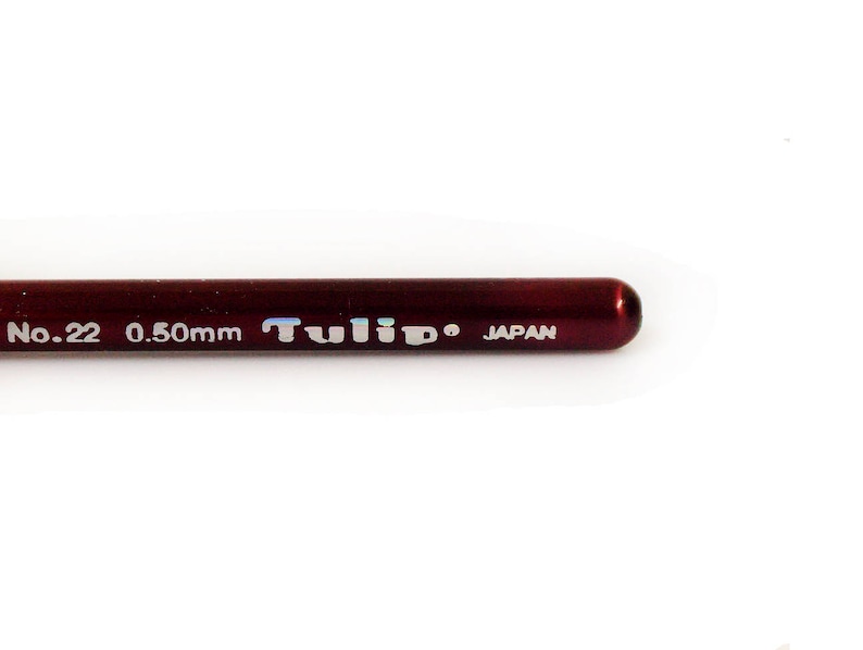 May include: Close-up of a red Tulip brand crochet hook with the text "No. 22 0.50mm JAPAN" printed on the side.