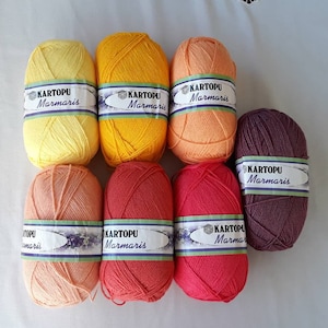 Puede incluir: Ocho ovillos de lana en varios tonos de naranja, rojo y morado. Cada ovillo tiene una etiqueta que dice "KARTOPU Marmaris".