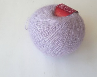 May include: A ball of light purple yarn with silver glitter threads. The yarn is wrapped around a red label with white text.