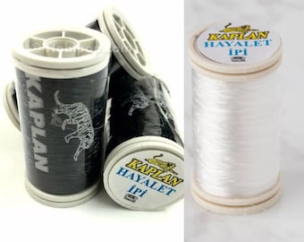 May include: Two spools of white thread, one black and one white, with the brand name "Kaplan Hayalet Ipi" printed on the label.