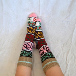 May include: Pair of colorful knitted socks with geometric patterns in shades of pink, brown, green, blue, and red.