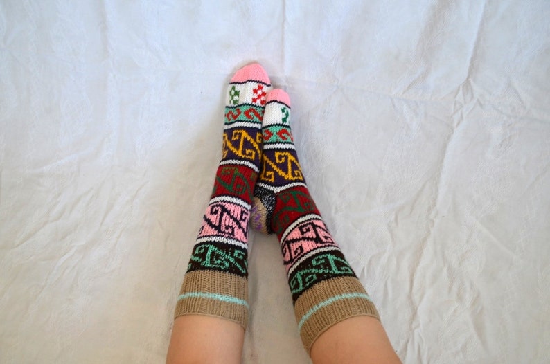 May include: Pair of colorful knitted socks with geometric patterns in shades of pink, brown, green, blue, and red.