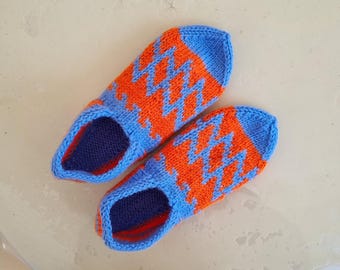 May include: A pair of blue and orange knitted slippers with a geometric pattern. The slippers are made of soft yarn and have a comfortable fit.