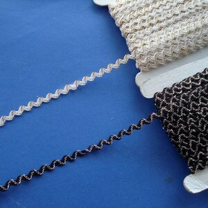 May include: Two spools of trim, one white with gold thread and one black with silver thread. Both trims have a wavy, zig-zag pattern.