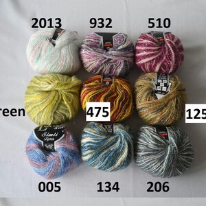 Puede incluir: Nueve ovillos de lana en varios colores y patrones, incluyendo verde, amarillo, rojo, morado, rosa, azul y gris. Cada ovillo tiene una etiqueta con un n&uacute;mero, como 2013, 932, 510, 475, 1252, 005, 134 y 206.