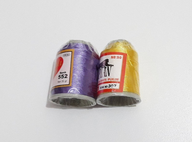 May include: Two spools of thread, one purple and one yellow. The purple spool has the text "Renk 552" and the yellow spool has the text "No:50 PLAN" and "Renk No:307".