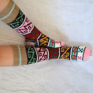 May include: A pair of colorful patterned socks with a brown cuff. The socks feature a geometric design with pink, green, yellow, red, and purple accents.