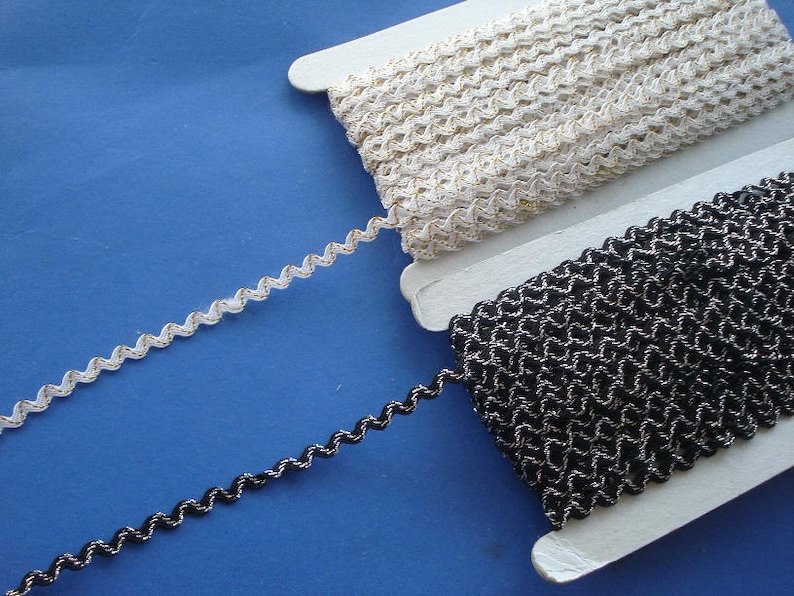 May include: Two spools of trim, one white and one black, with a wavy, zig-zag pattern. Both trims have a metallic sheen.