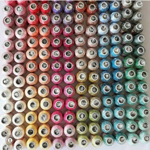 May include: A large collection of colorful spools of thread, arranged in rows and columns. The spools are all the same size and shape, and they are wrapped in a variety of colors, including red, orange, yellow, green, blue, purple, and pink.