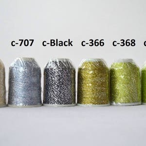 May include: Six spools of metallic thread in various colors, including cream, silver, black, gold, green, and lime green. The spools are labeled with their color codes: c-Cream, c-707, c-Black, c-366, c-368, and c-703.