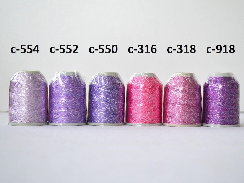 May include: Six spools of metallic embroidery thread in various shades of purple and pink. The spools are labeled with the following color codes: c-554, c-552, c-550, c-316, c-318, and c-918.