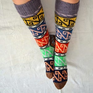 May include: A pair of colorful knee-high socks with a geometric pattern in shades of brown, orange, red, green, blue, yellow, and white. The socks are made of a soft, knitted fabric.