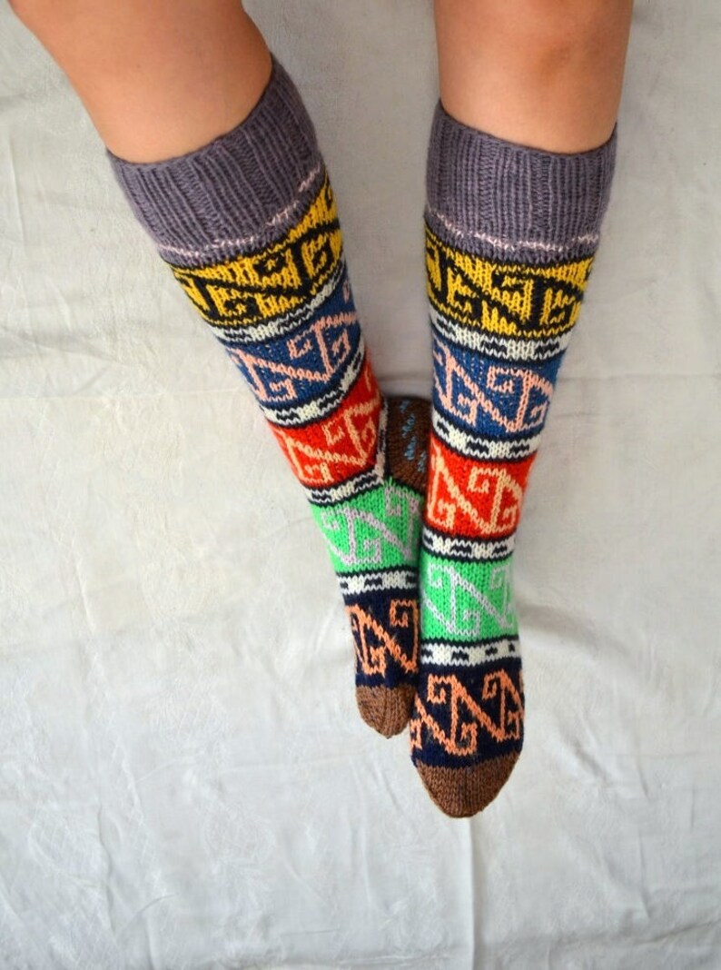 May include: A pair of colorful knee-high socks with a geometric pattern in shades of brown, orange, red, green, blue, yellow, and white. The socks are made of a soft, knitted fabric.