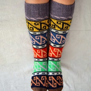 May include: A pair of colorful knitted socks with a geometric pattern. The socks are grey at the top and have brown heels and toes.