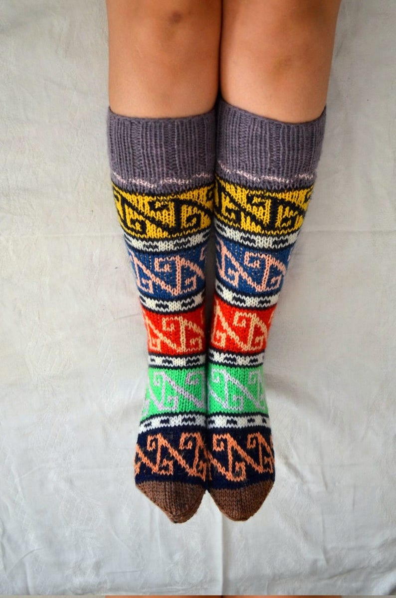 May include: A pair of colorful knitted socks with a geometric pattern. The socks are grey at the top and have brown heels and toes.