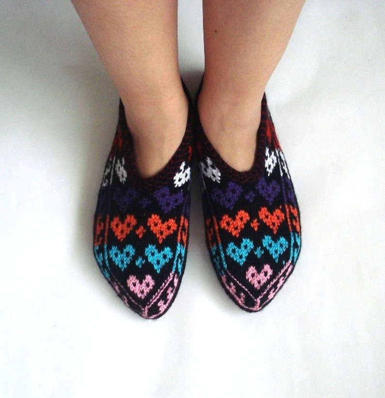 May include: A pair of black knitted slippers with a colorful heart pattern. The pattern features pink, blue, orange, and purple hearts.