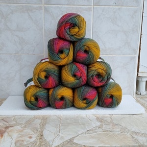 May include: A stack of nine balls of yarn in a triangular shape. The yarn is a mix of green, yellow, and red.