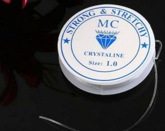 Può includere: Una bobina di filo per perline elastico trasparente. L'etichetta bianca recita "STRONG & STRETCHY" e "CRYSTALINE" con una grafica a diamante. La dimensione è indicata come 1.0. Il filo è per la creazione di gioielli e l'artigianato.