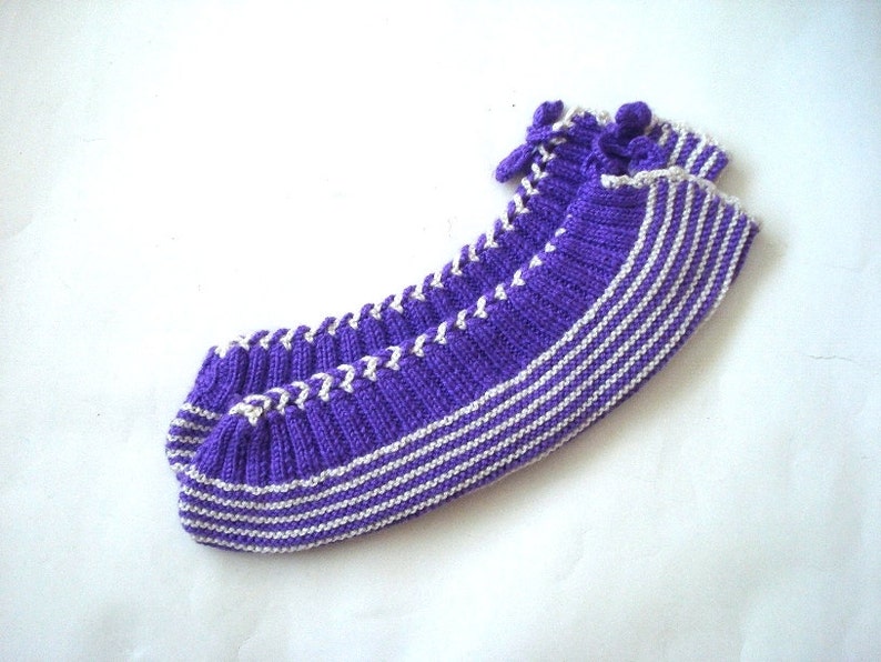 May include: Purple and white striped knitted slipper socks with a white braided trim.