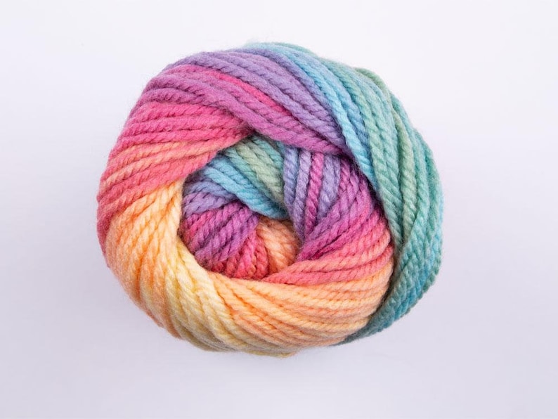 May include: A ball of yarn with a rainbow ombre color pattern. The yarn is a mix of light pink, yellow, orange, blue, and green.
