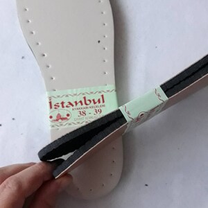 May include: A pair of white shoe insoles with black stitching and a green and white label that reads "Istanbul Ayakkabı Keceleri 38-39" in red lettering.