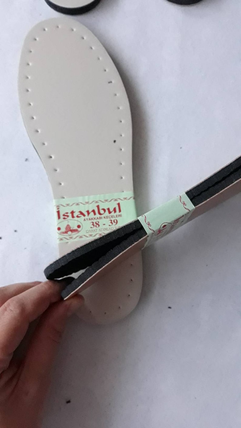 May include: A pair of white shoe insoles with black stitching and a green and white label that reads "Istanbul Ayakkabı Keceleri 38-39" in red lettering.