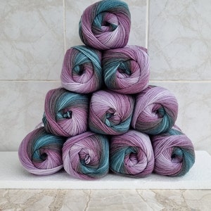 May include: A stack of ten balls of yarn in shades of purple, green, and brown. The yarn is arranged in a pyramid shape.