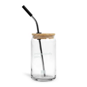 May include: A clear glass tumbler with a bamboo lid and a metal straw. The glass features the text "professionally petty" printed in a light color. The straw is bent at the top and has a black silicone tip for comfortable drinking.