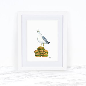 Puede incluir: Una pintura de acuarela de una gaviota de pie sobre una pila de cinco hamburguesas. La gaviota mira hacia la izquierda y tiene una cabeza blanca y un cuerpo gris. Las hamburguesas son marrones y tienen lechuga verde y queso amarillo.