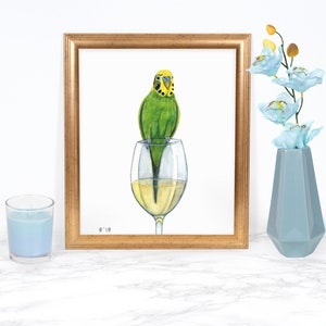 Puede incluir: Una pintura de acuarela de un periquito verde posado en el borde de una copa de vino llena de vino blanco. La pintura est&aacute; enmarcada en un marco dorado y firmada "9'18".