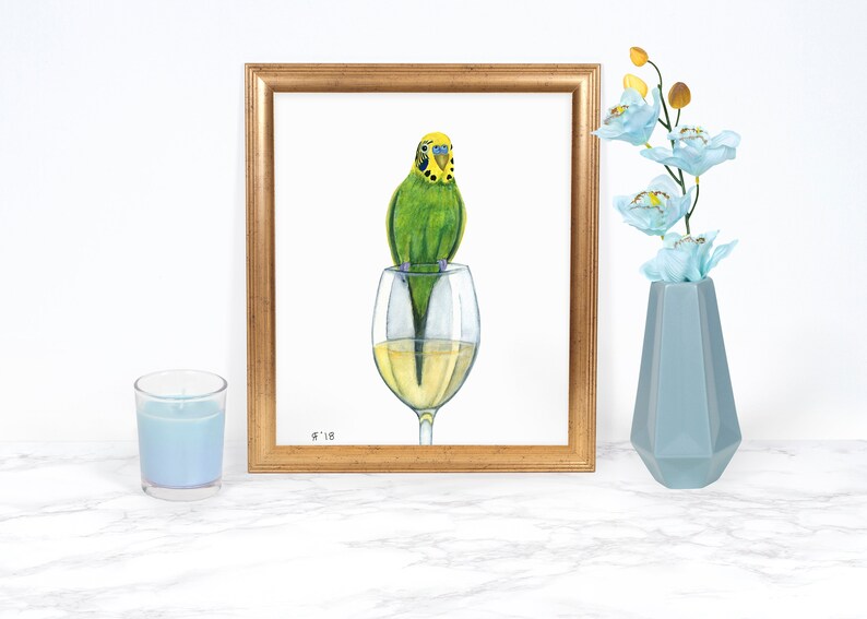 Puede incluir: Una pintura de acuarela de un periquito verde posado en el borde de una copa de vino llena de vino blanco. La pintura est&aacute; enmarcada en un marco dorado y firmada "9'18".