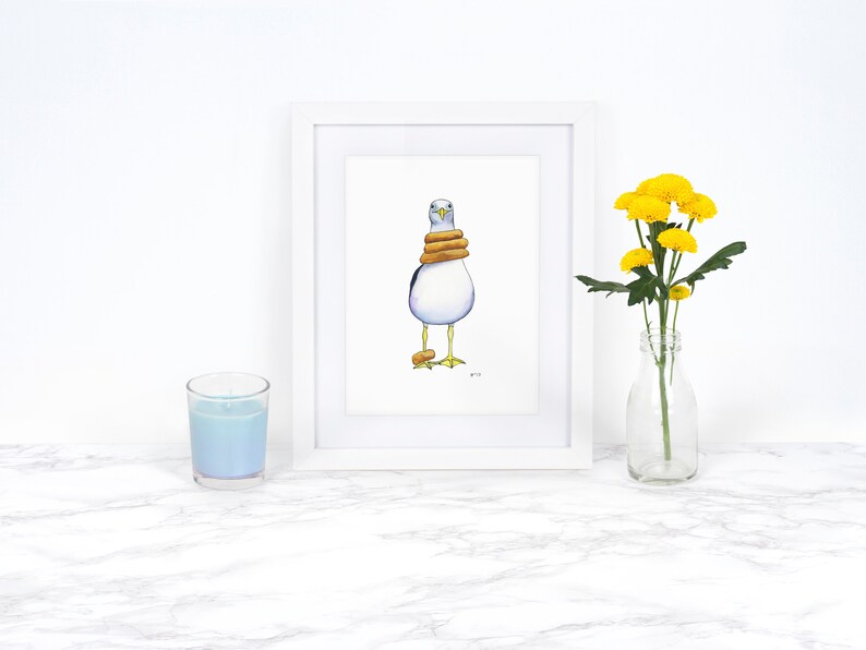 May include: A white framed print of a watercolor painting of a seagull wearing a stack of three yellow life preservers. The seagull is standing on a white background.