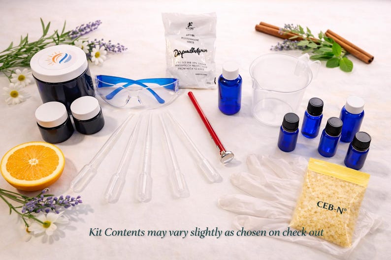 May include: A candle making kit featuring a large dark blue jar, two small dark blue jars, blue safety glasses, a white apron, a red thermometer, five plastic pipettes, a clear measuring beaker, six small blue bottles, and a bag of wax beads labeled CEB-N.