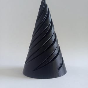 May include: A matte black conical object featuring a series of deep, spiraling grooves that wrap around the exterior from the wide circular base to the pointed apex. The surface displays a fine, layered texture consistent with additive manufacturing.