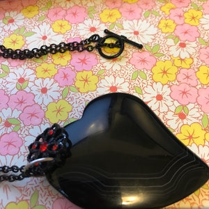 Tumbled black obsidian heart shaped stone, with black and red flower charm attached.