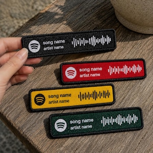 May include: Four rectangular embroidered patches featuring the Spotify logo, the text song name and artist name, and a sound wave graphic. The patches come in black, red, yellow, and green, each with a contrasting border and stitched details.
