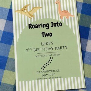Puede incluir: Una invitación de cumpleaños rectangular con fondo de rayas verde claro y blanco y un arco central. Muestra un pterodáctilo color canela y un dinosaurio de cuello largo color melocotón, con el texto Roaring Into Two, Luke's 2nd Birthday Party.