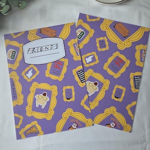 May include: Two rectangular purple sheets featuring a repeating pattern of yellow picture frames, the Central Perk logo, a turkey with sunglasses, a couch, and text including FRIENDS, OH MY GOD, HES HER LOBSTER, and character names.