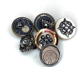 May include: Six vintage buttons in various colours and designs. The buttons are made of metal, plastic, and shell. They feature intricate patterns and details.