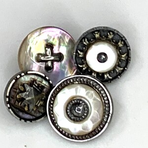 Puede incluir: Cuatro botones vintage con un acabado nacarado. Un botón tiene un diseño de cruz, otro tiene un diseño de estrella y dos tienen un diseño circular con un círculo más pequeño en el centro.