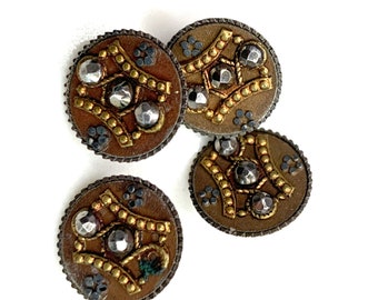 May include: Four round, brown, metal buttons with gold accents and silver rhinestones. The buttons have a decorative design with a central star shape.