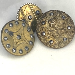 Puede incluir: Tres botones antiguos de latón con diseños decorativos y tachuelas de plata. Los botones son redondos y tienen un diseño en relieve.
