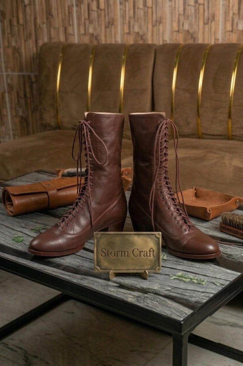 May include: A pair of mid-calf brown leather lace-up boots with rounded toes and stacked heels. The boots feature long matching laces tied at the top. A rectangular brass plaque stands in front of the boots with the text Storm Craft engraved.