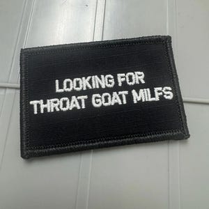 May include: A rectangular black embroidered patch with a stitched border. The text LOOKING FOR THROAT GOAT MILFS is embroidered in white capital letters across the center of the patch, featuring a clean, bold, and sans-serif font style.